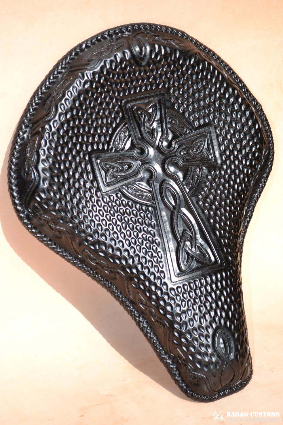 "CROSS" design hand tooled and braided on a chopper solo seat. Black Veg tan leather with kangaroo lace.