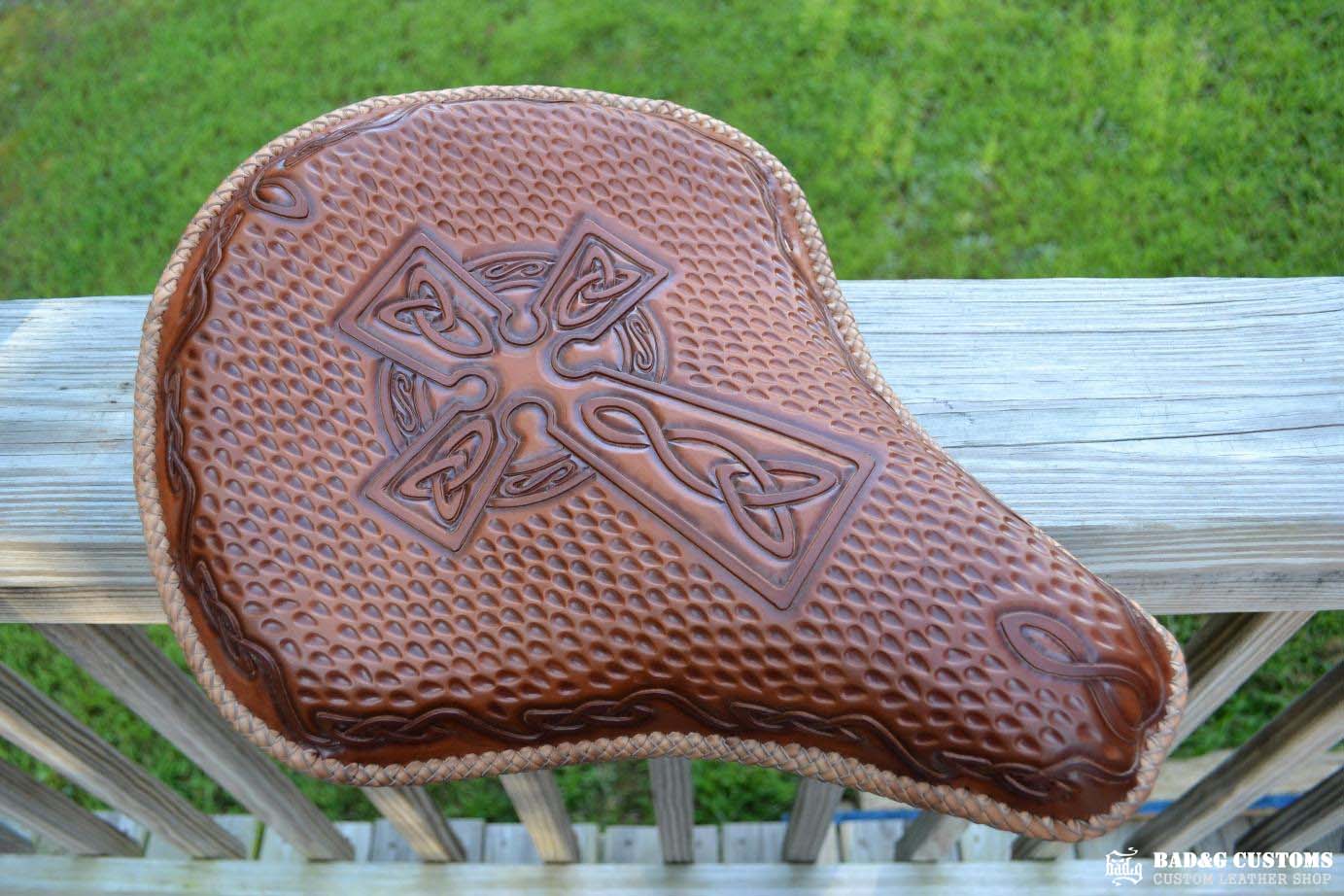 "CROSS" design hand tooled and braided on a chopper solo seat. Brown Veg tan leather with kangaroo lace.